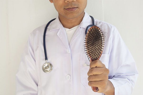 Un médecin tenant une brosse à cheveux à la main. chirurgien de greffe de cheveux