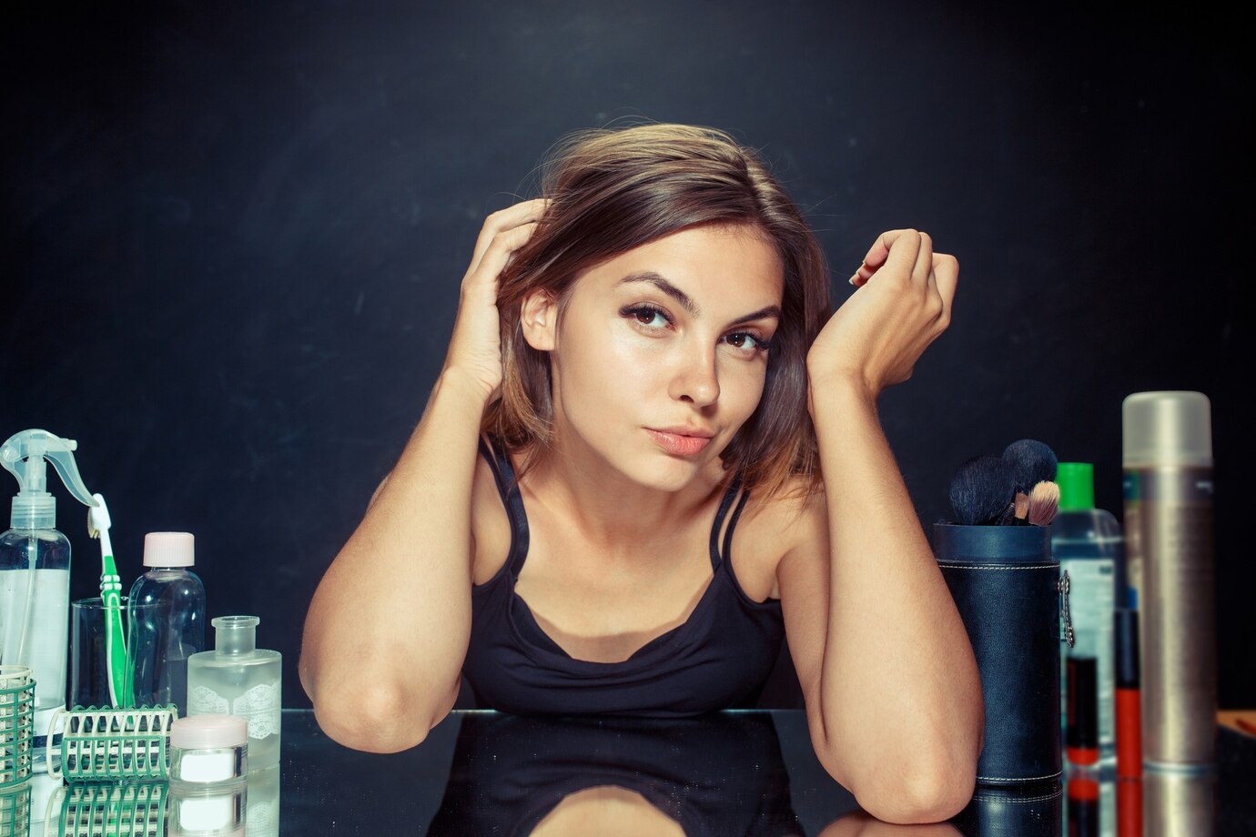 Belle femme après s'être maquillée. Belle fille se regardant dans le miroir. Concept du matin, du maquillage et des émotions humaines. Modèle caucasien dans le studio. débarrasser des pellicules chez les femmes
