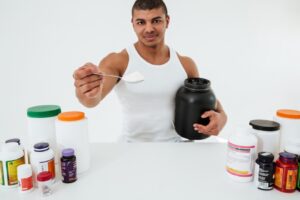 Sportif debout sur un mur blanc tenant des vitamines