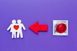 Couple en papier à côté d'un préservatif rouge. chlamydia 