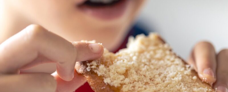 Un enfant mange du pain avec du fromage râpé gros plan. Intolérance au gluten Comment l'identifier