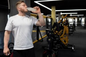 Homme en train de boire une boisson à la salle de sport