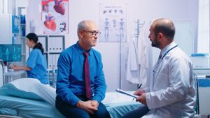Les hommes âgés à la retraite dans une clinique privée moderne répondant au questionnaire du médecin assis sur un lit d'hôpital. Les patients âgés et malades cherchent des conseils médicaux pour la prévention des maladies auprès d'un médecin généraliste dans une clinique privée moderne.