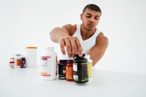Sportif debout sur un mur blanc tenant des vitamines. Qu'est-ce que la créatine