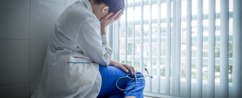 Femme médecin dépressive assise en désespoir de cause près d'une fenêtre d'hôpital - concept de soins de santé et de chagrin. Qu'est-ce que l'ostéonécrose
