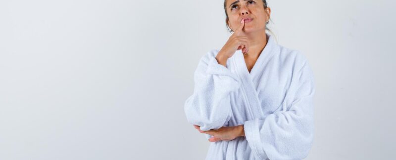Jeune femme en peignoir, debout, en train de réfléchir, l'air pensif. Qu'est-ce qu'un sarcome