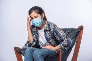La femme, malade, s'est assise sur une chaise et s'est touché la tête avec la main.