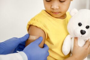 Un médecin colle un pansement sur l'épaule d'une fillette après une vaccination