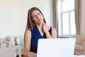 Jeune femme d'affaires souffrant de maux de cou et se massant la nuque en s'asseyant.