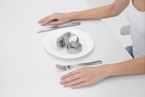 Jeune femme souffrant d'un trouble de l'alimentation ayant un mètre ruban sur la plaque