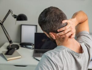 Vue de dos d'un homme s'étirant tout en travaillant à domicile