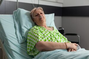 Portrait d'une retraitée malade regardant l'appareil photo alors qu'elle se repose dans son lit. Maladie de Huntington. Types d'hépatites