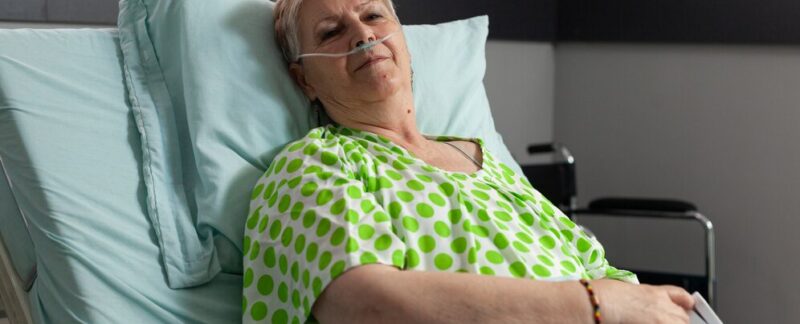Portrait d'une retraitée malade regardant l'appareil photo alors qu'elle se repose dans son lit. Maladie de Huntington