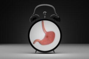 Concept de nutrition par intervalles Réveil avec estomac sur le cadran Fond sombre Rendu 3D