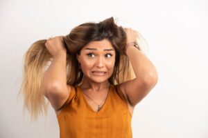 Jeune femme se touchant les cheveux et posant sur fond blanc.