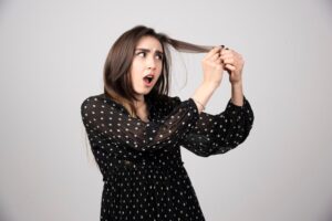 Une belle jeune femme tenant ses cheveux sains et brillants. Qu'est-ce que la trichotillomanie