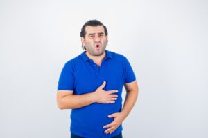 Homme d'âge moyen en polo souffrant de douleurs à l'estomac. Qu'est-ce que le reflux gastrique