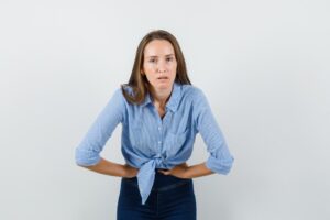 Dame souffrant de maux d'estomac, vêtue d'une chemise et d'un pantalon bleus. Incontinence urinaire chez l'homme et la femme