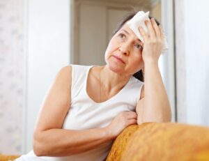 Mature woman uses handkerchief on head. Maladie de Huntington 