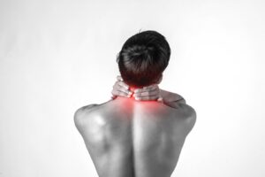 Un homme musclé utilise des poignées au niveau du cou pour soulager la douleur, isolé sur fond blanc.