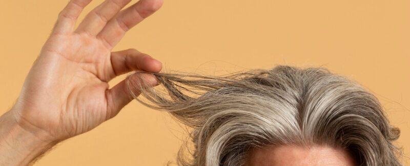 Un vieil homme tenant ses cheveux gris. Greffe de cheveux avec des cheveux gris : est-ce possible ?