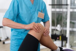 Assistante médicale aidant le patient à faire des exercices de physiothérapie.